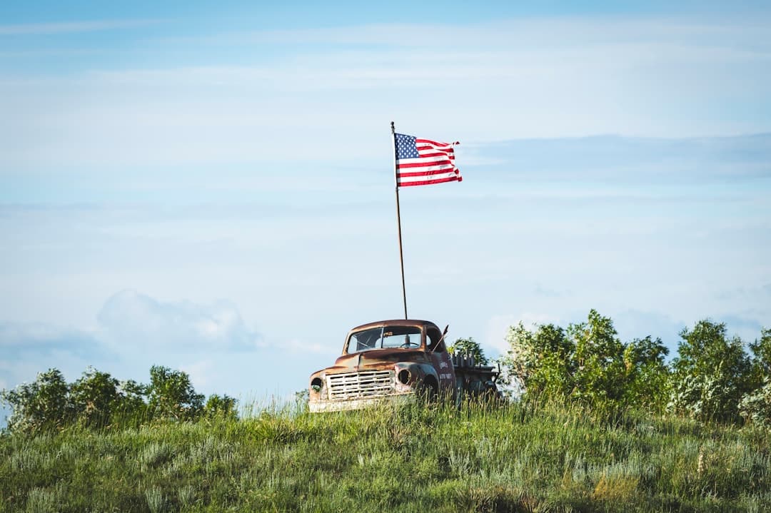 an old truck with an american flag on top of it